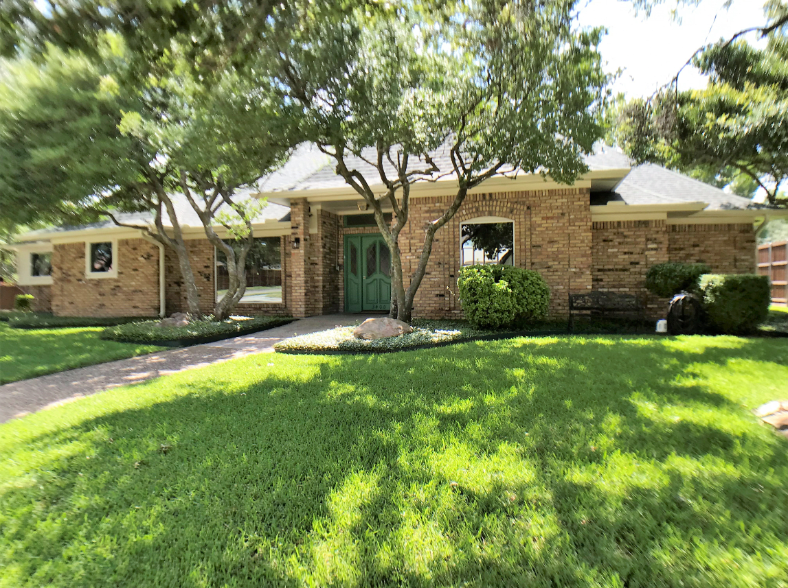 A brick house with a well-maintained front yard and trees.
