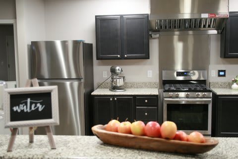 A modern kitchen with stainless steel appliances and a bowl of apples on the countertop.