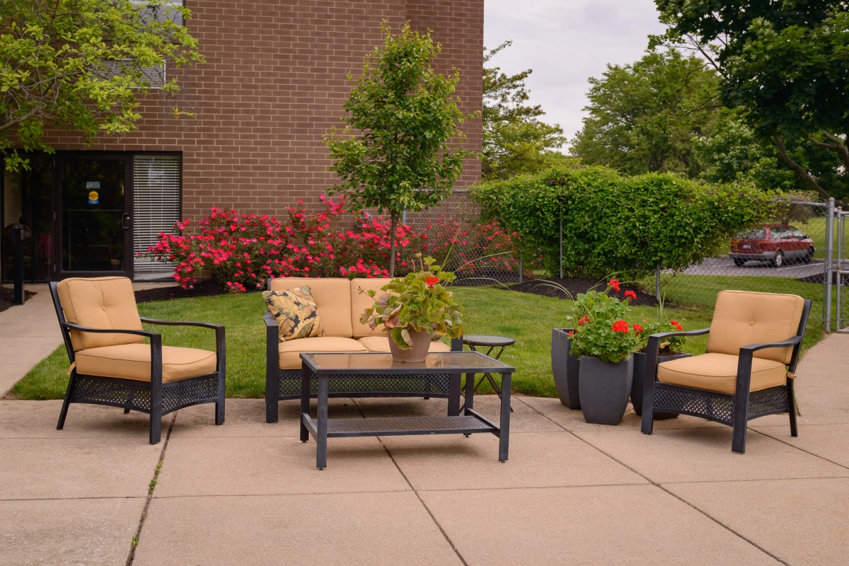 A cozy outdoor seating area with patio furniture surrounded by lush greenery and vibrant flowers.