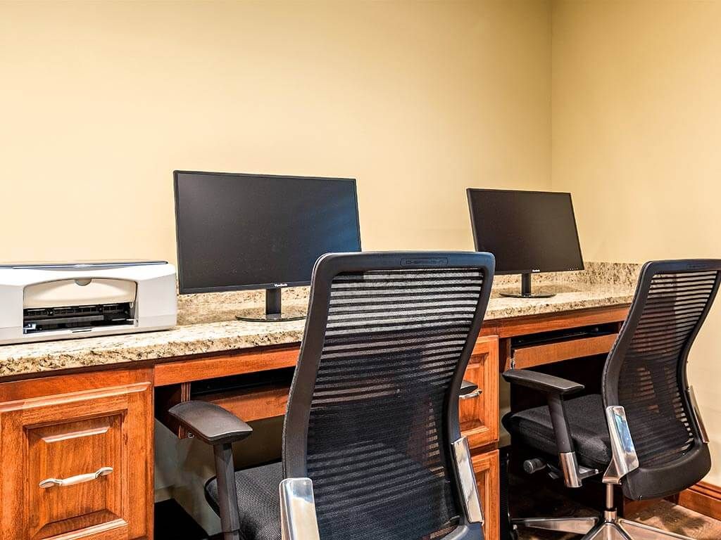 A small office setup with desks, monitors, and chairs.