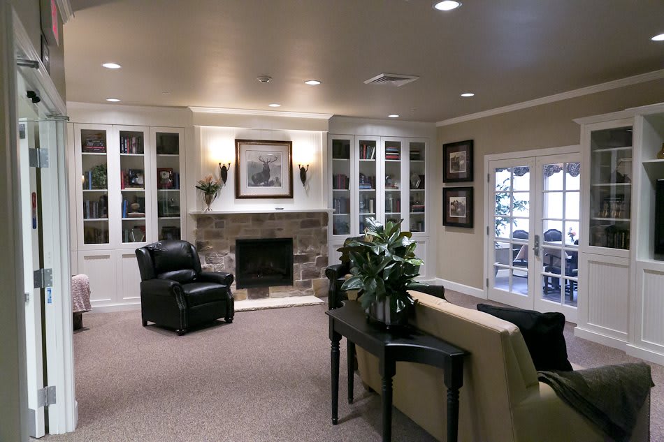 A cozy living room featuring a fireplace, armchairs, and built-in bookshelves.