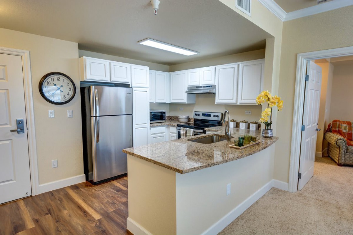 A modern kitchen featuring stainless steel appliances and granite countertops with white cabinetry.