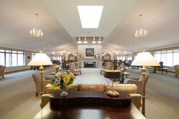 A spacious and elegantly furnished living room with multiple seating areas and a central fireplace.