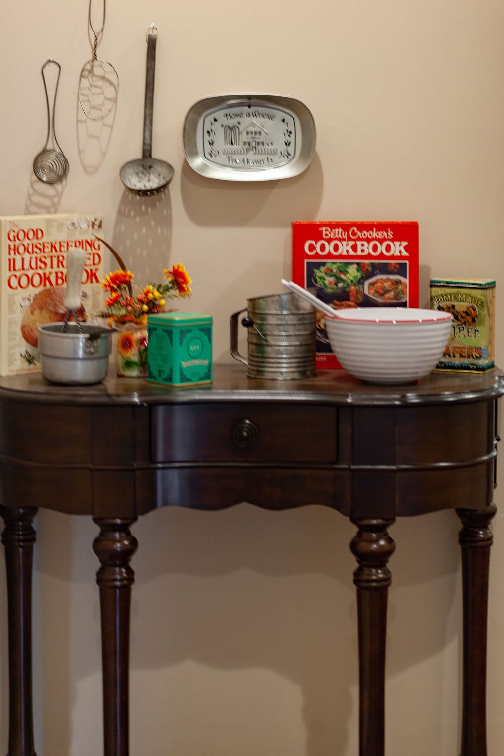 A vintage kitchen setup featuring cookbooks and baking tools on a wooden table.