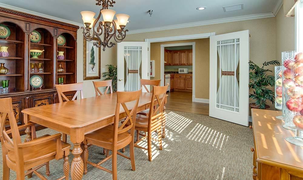 A cozy dining room with a wooden table and chairs, illuminated by an elegant chandelier, featuring sliding doors that lead to the kitchen.