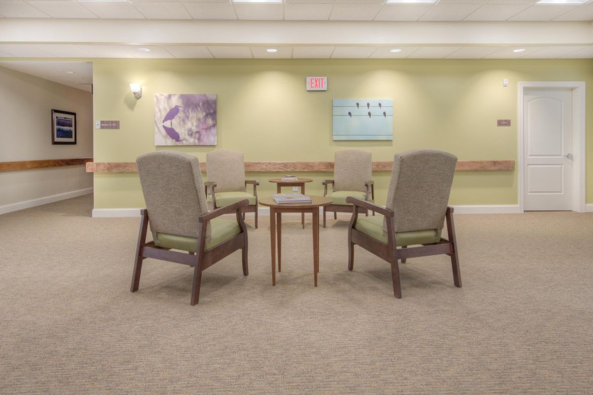 An empty waiting area with four upholstered chairs surrounding a small table, featuring artwork on the walls.