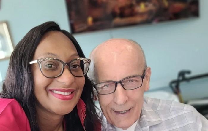 Two people smiling for a selfie indoors.