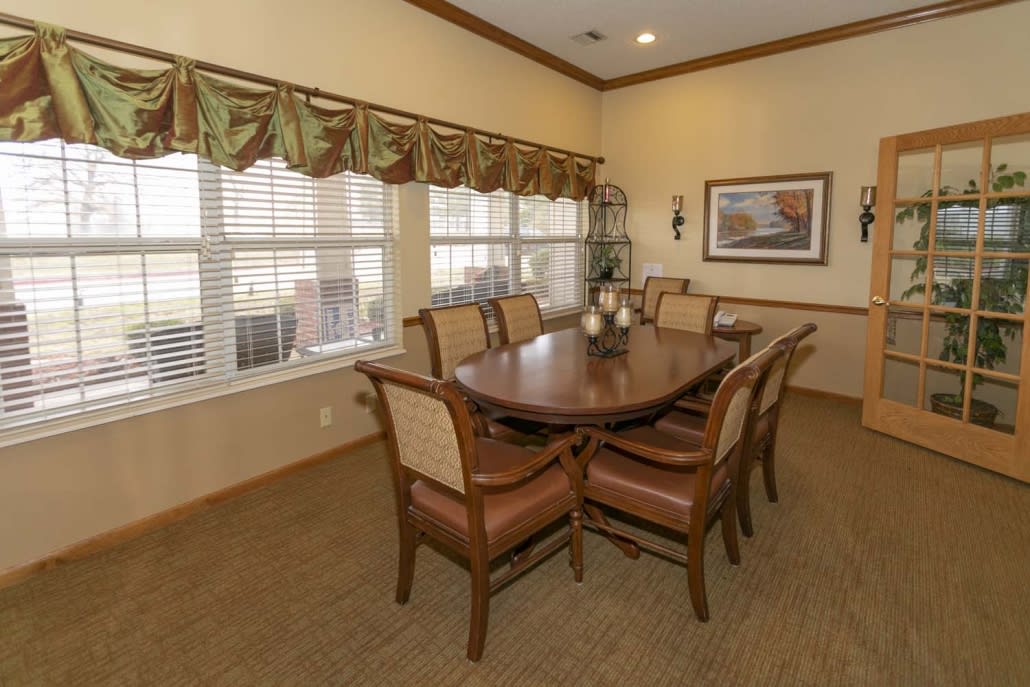 A cozy dining room with a wooden table and chairs, decorated with elegant curtains and artwork.