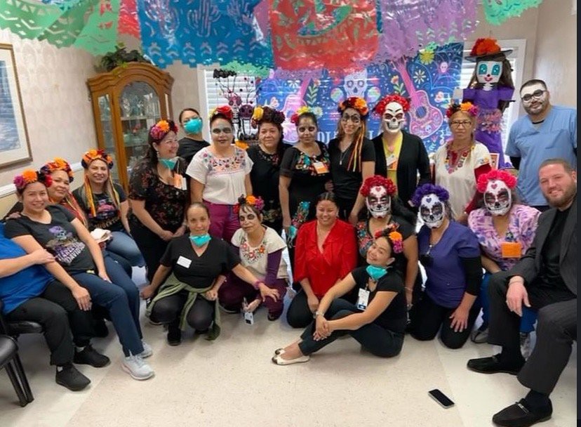 A group of people in festive costumes and face paint gather for a celebration.