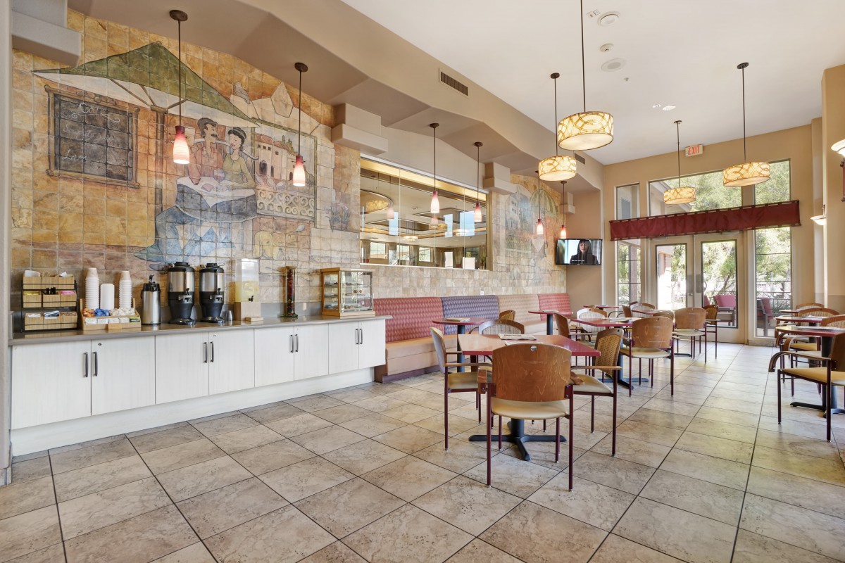 A cozy restaurant interior with tables, chairs, and decorative murals.