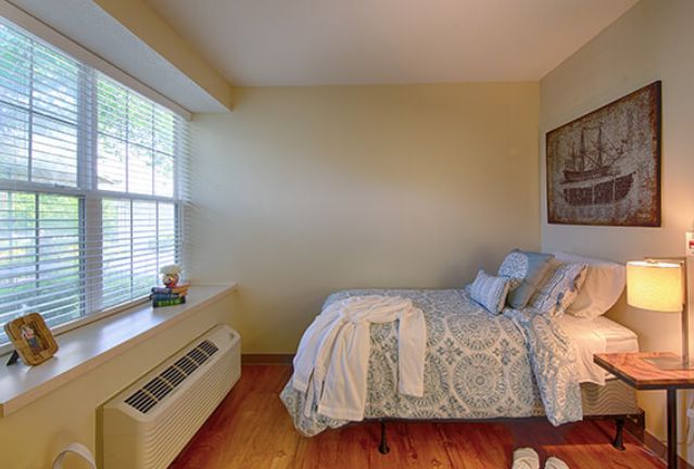 A cozy bedroom with a bed near a large window, allowing natural light to fill the room.