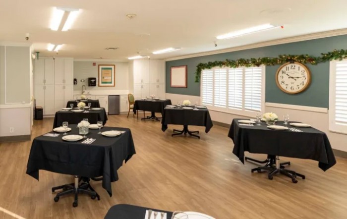 A neatly arranged dining area with tables covered in black tablecloths and simple decor.