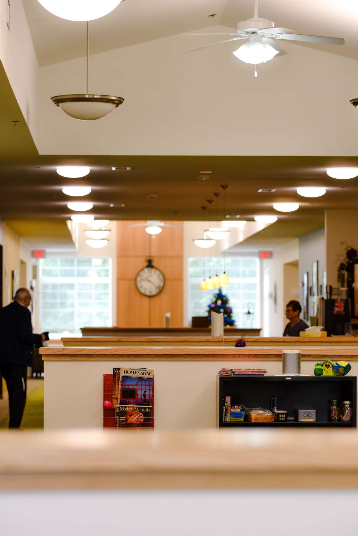 A modern library interior with bookshelves, a clock, and people studying.