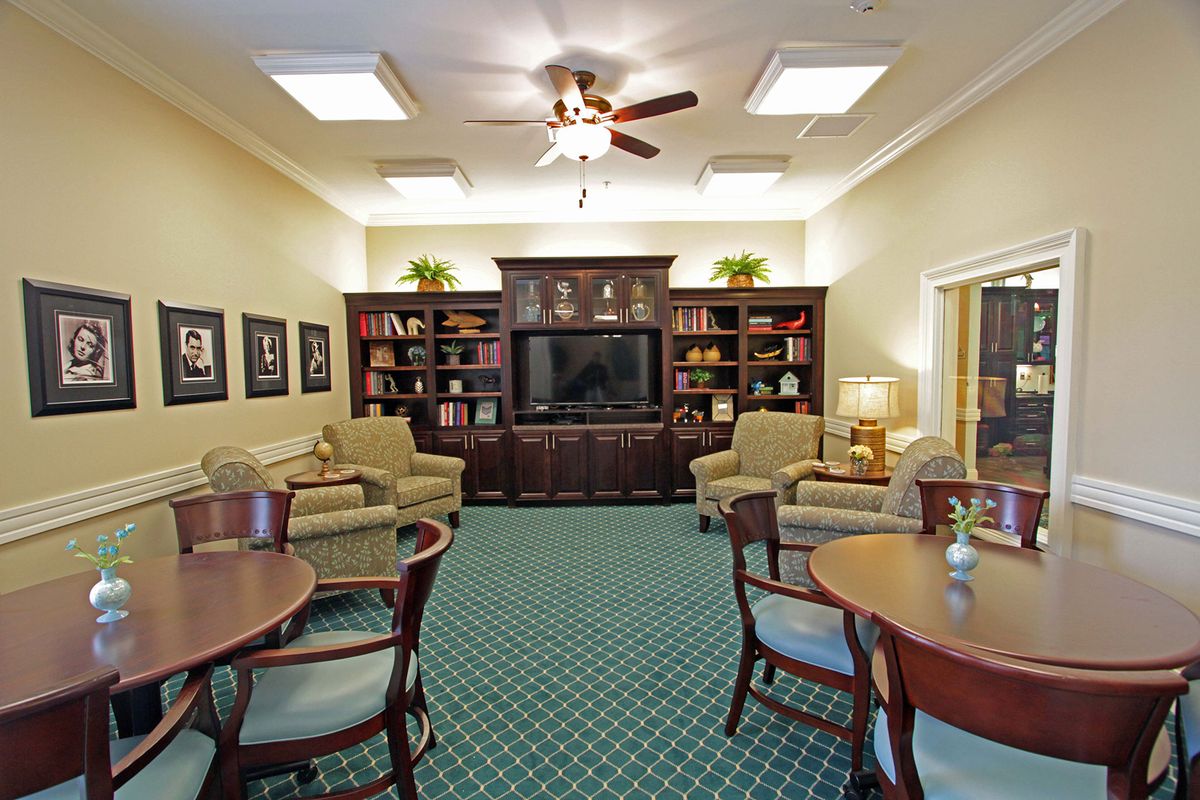 A cozy living room with comfortable seating, bookshelves, and a large television.