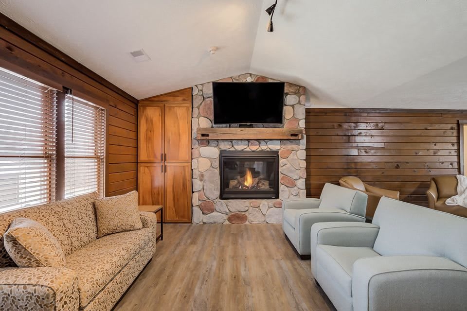 A cozy living room with a stone fireplace and comfortable seating.