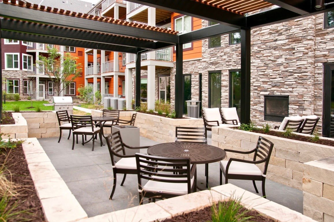 A modern outdoor patio area with tables and chairs, surrounded by contemporary architecture.