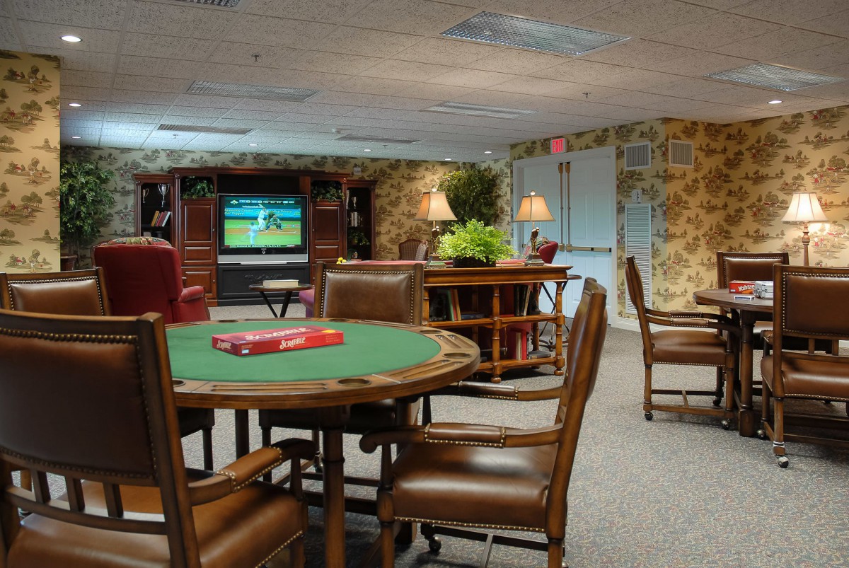 A cozy game room with a poker table, comfortable chairs, and a large TV for entertainment.