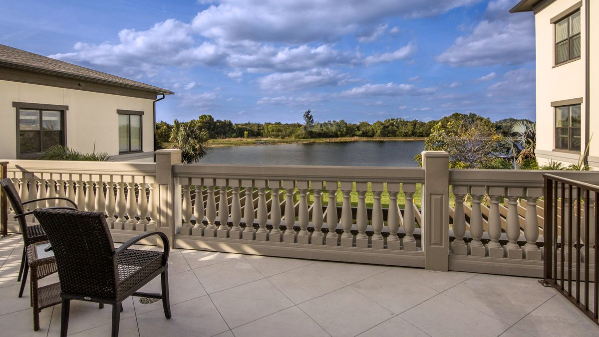 A serene balcony overlooking a tranquil lake under a partly cloudy sky.