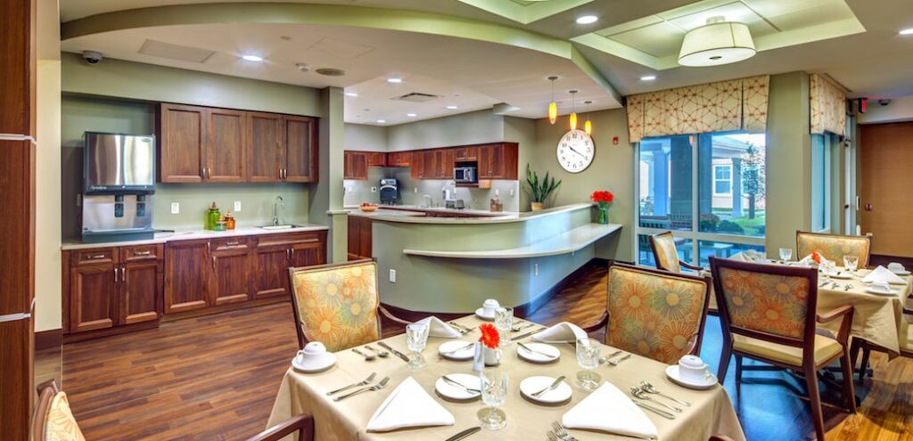 A modern dining area with a neatly set table and an open kitchen in the background.