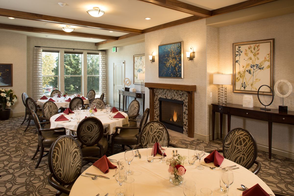 Elegant dining room with round tables set for a meal, featuring a cozy fireplace.