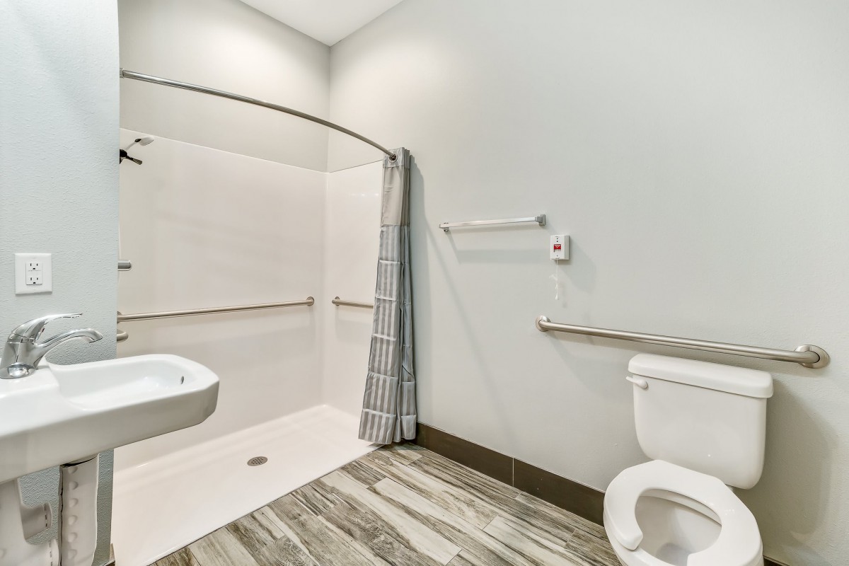 An accessible bathroom with a walk-in shower, toilet, and grab bars.