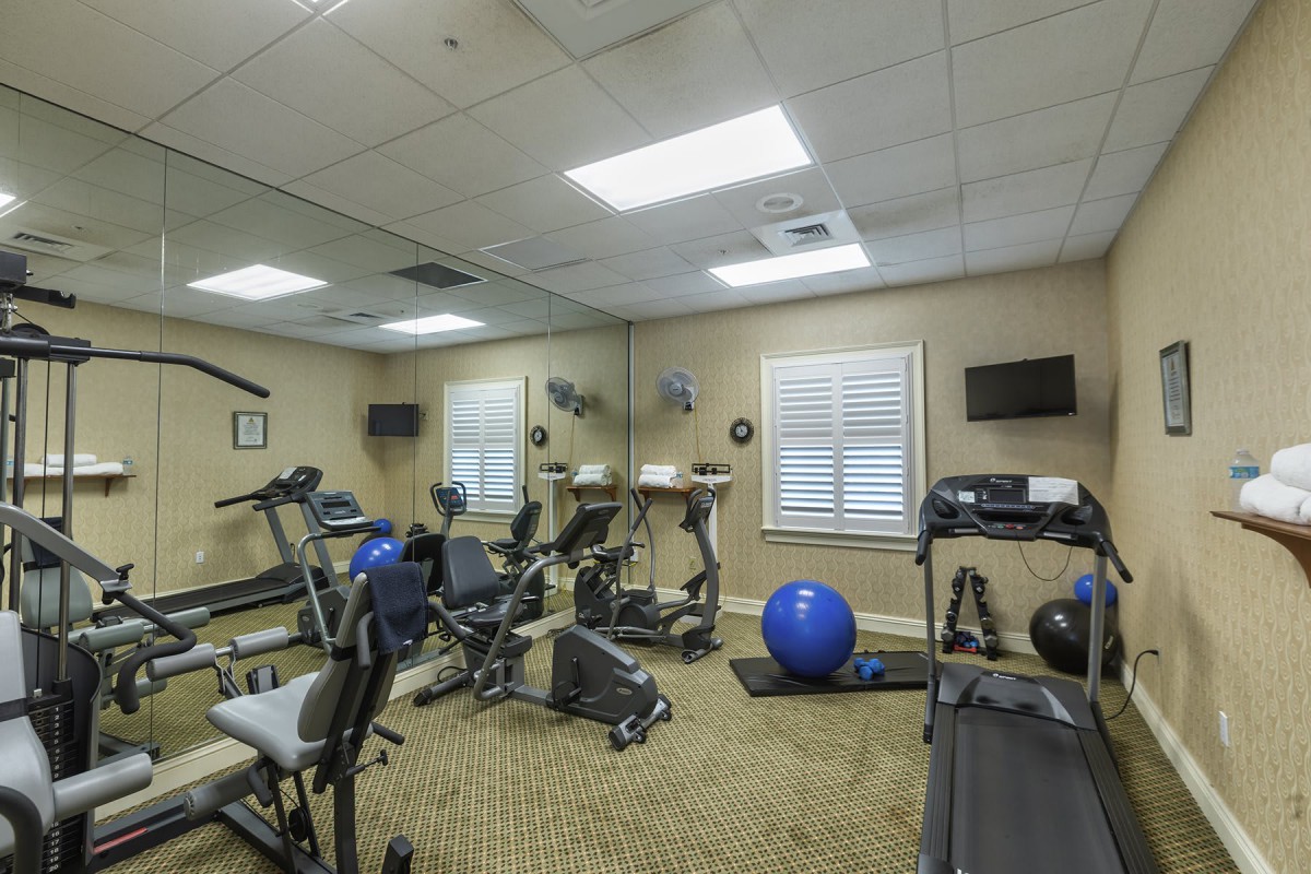 A small indoor gym with various fitness equipment including treadmills and an exercise ball.
