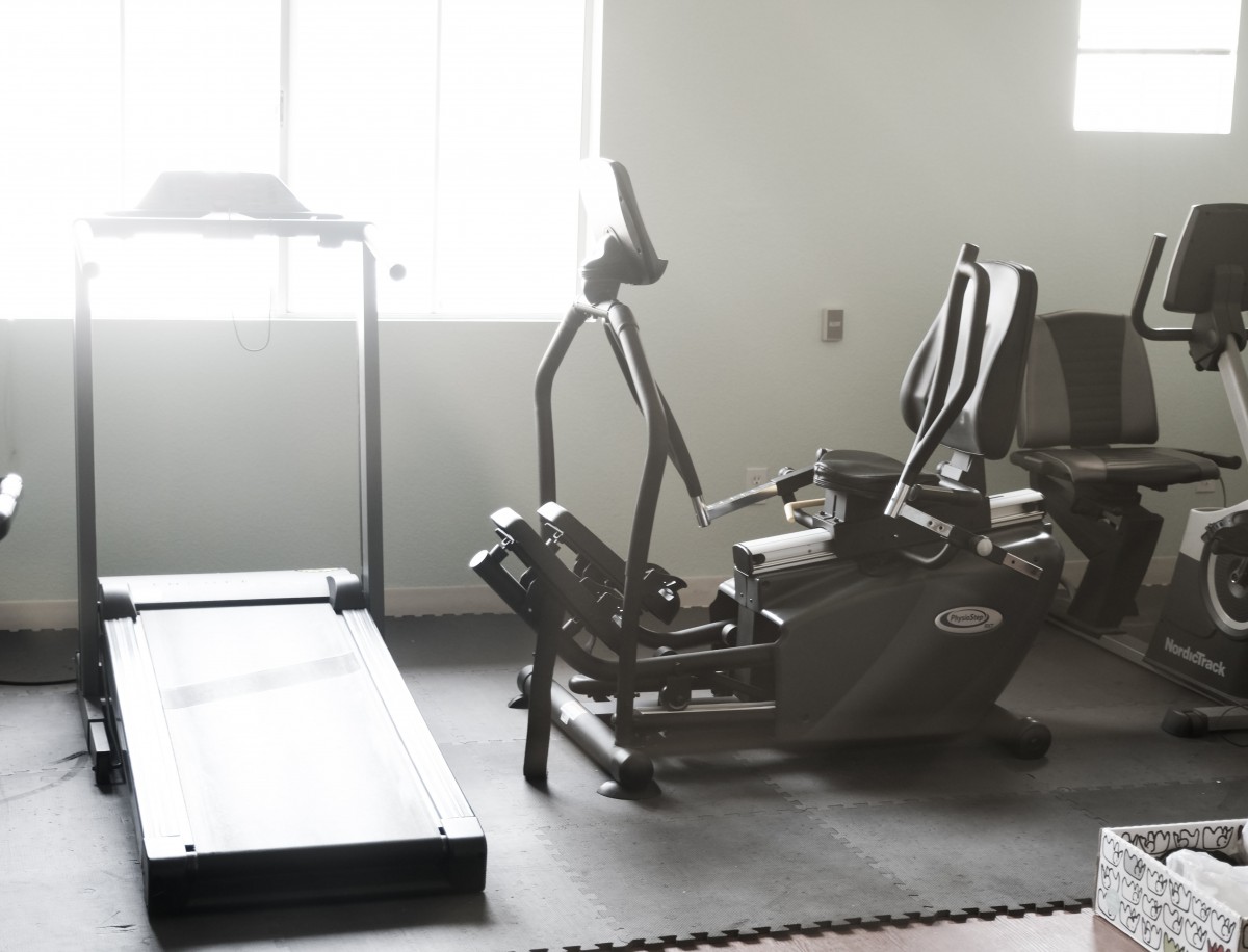 A well-lit workout room with a treadmill and exercise bike.