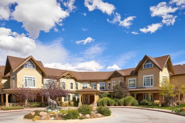 A charming residential building with a beautifully landscaped garden under a clear blue sky.