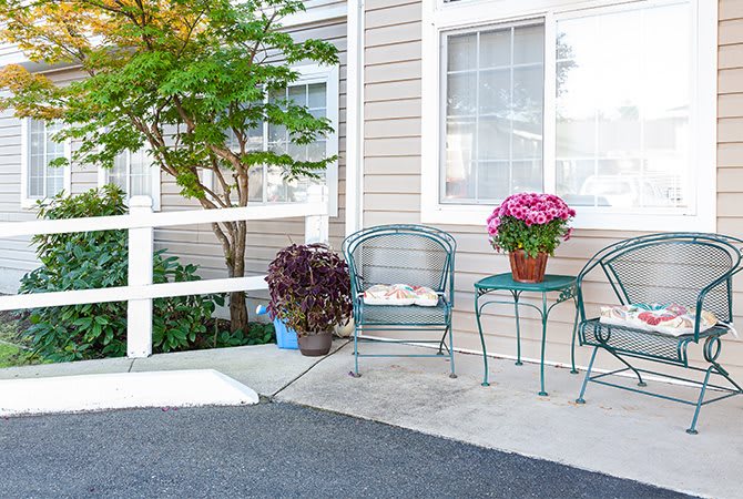 A cozy patio setting with metal chairs, a small table, and potted plants by a fence.