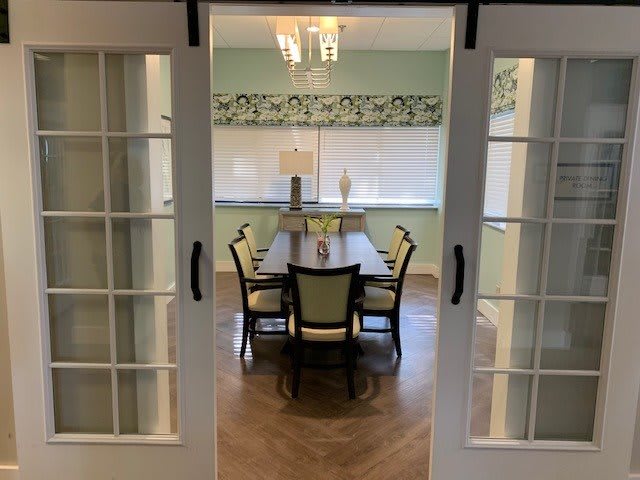 A dining room viewed through a doorway featuring a table and chairs under a chandelier.