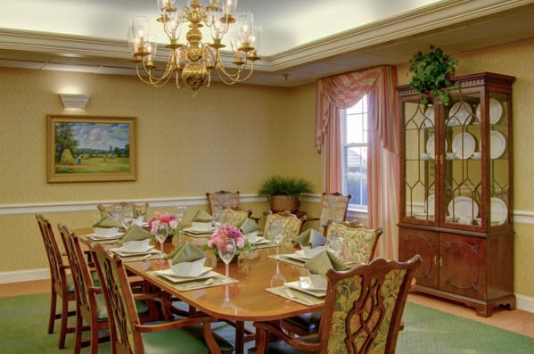 An elegant dining room with a formal table setting and chandelier.