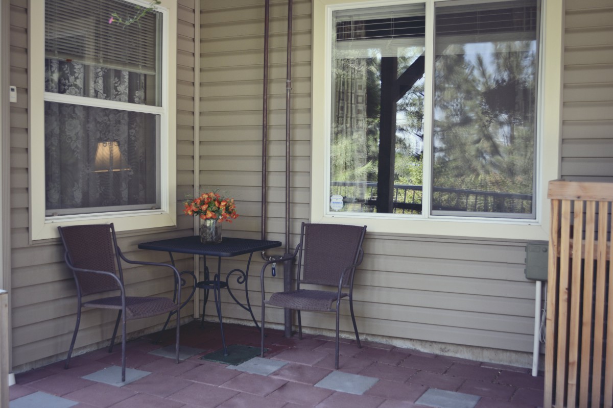 A cozy patio area with a table, two chairs, and a window view.