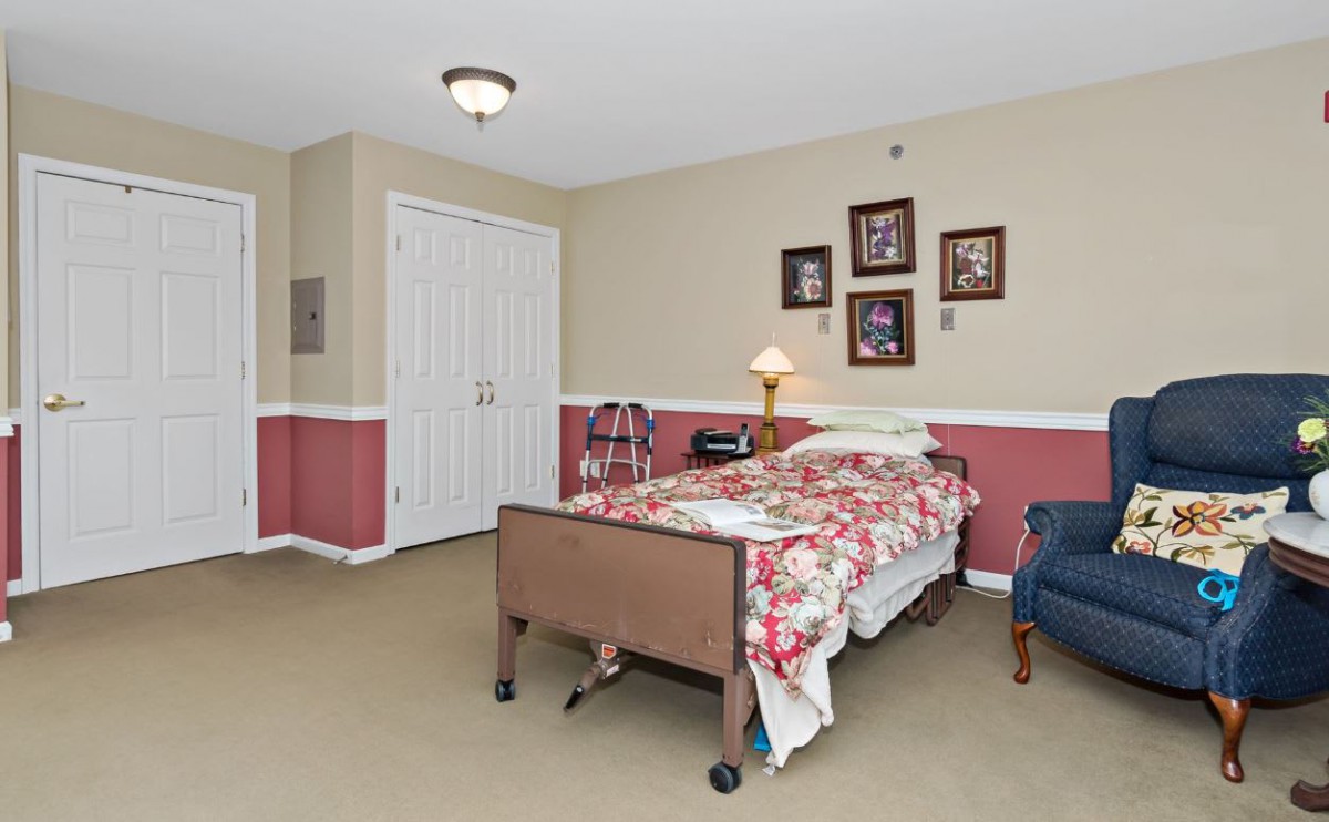 A cozy bedroom with a hospital bed, featuring floral bedding and decorative wall photos.