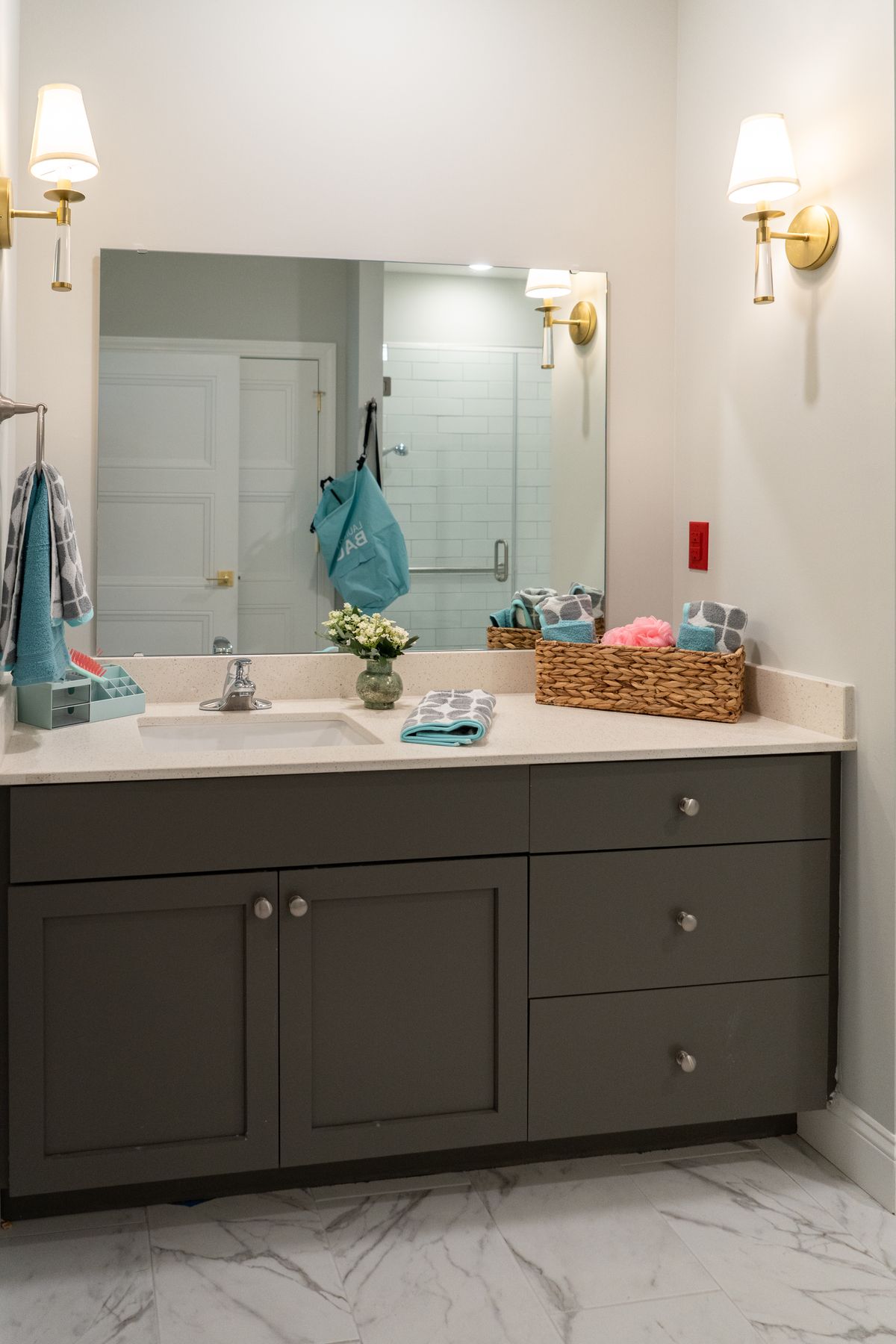 A neatly organized bathroom vanity with a large mirror and a basket of toiletries.