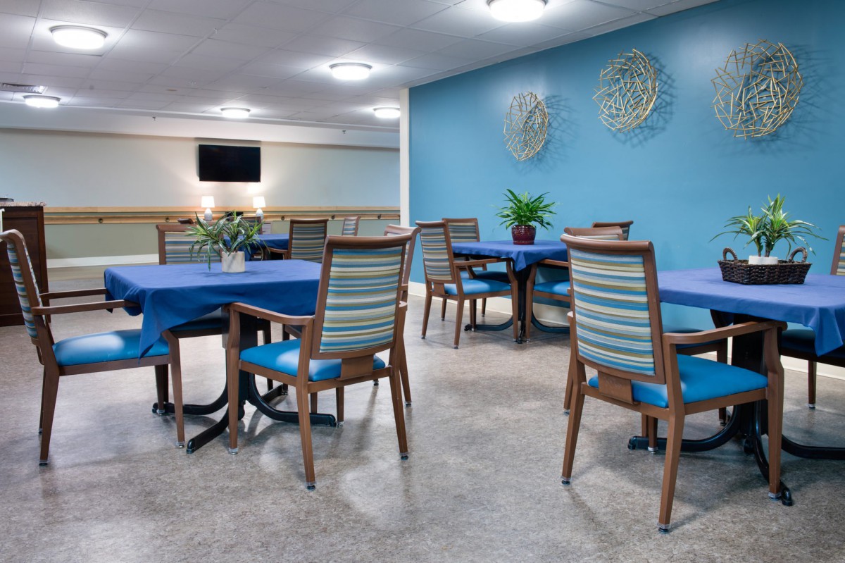 A dining room with blue-accented decor, featuring striped chairs and tables set against a bright wall.