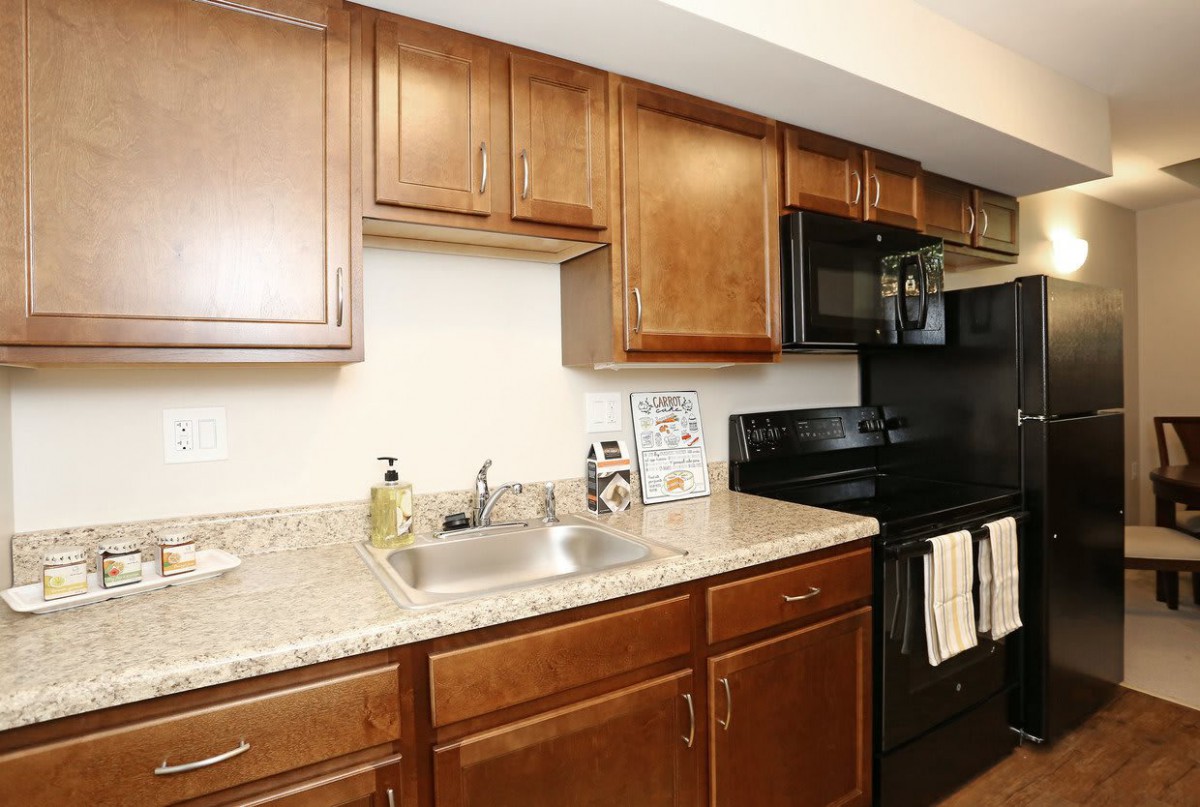 Modern kitchen with wooden cabinets and black appliances.