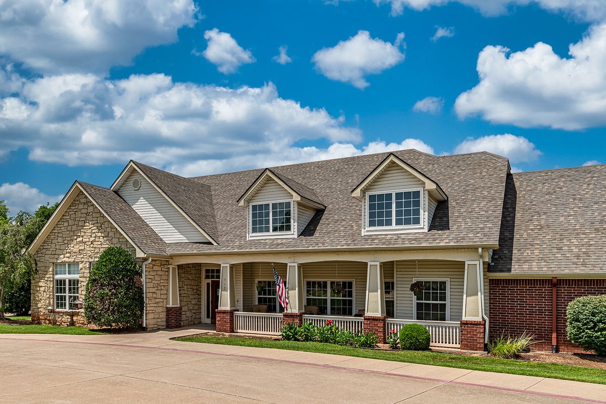 A suburban house with a spacious front yard under a partly cloudy sky.