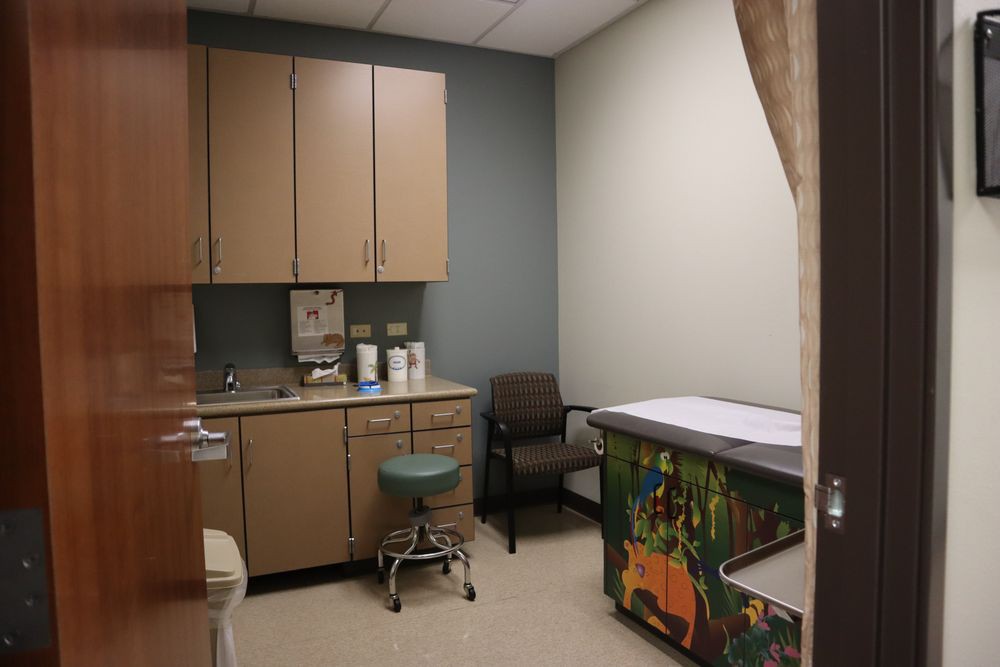 A clean and organized examination room in a doctor's office with medical equipment and furniture.