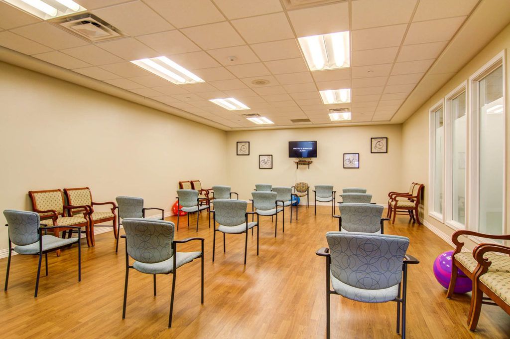 An empty meeting room with arranged chairs and a television.