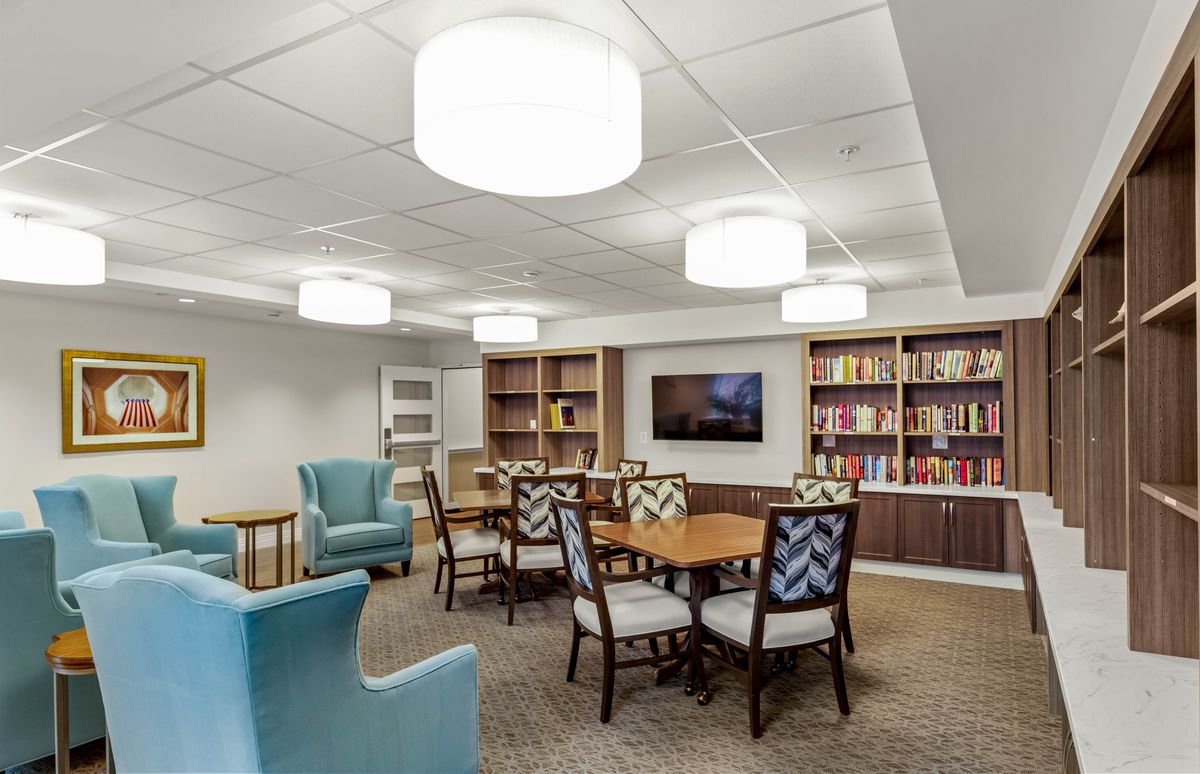 A cozy reading room with bookshelves, tables, and comfortable seating.