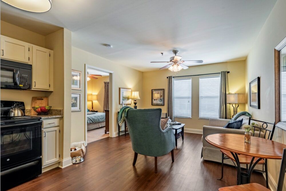 A cozy living room with wooden floors, a ceiling fan, and comfortable seating.
