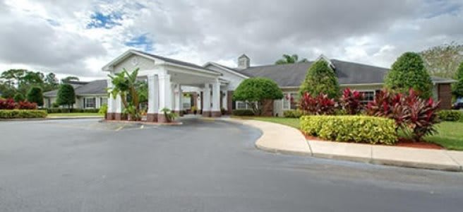 A well-maintained building with a driveway surrounded by lush greenery under a cloudy sky.