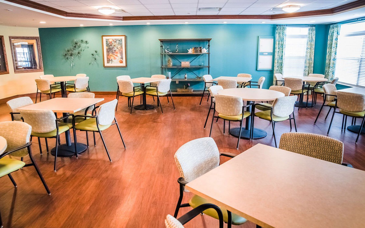 A cozy dining area with neatly arranged tables and chairs, featuring a wooden floor and decorative elements.