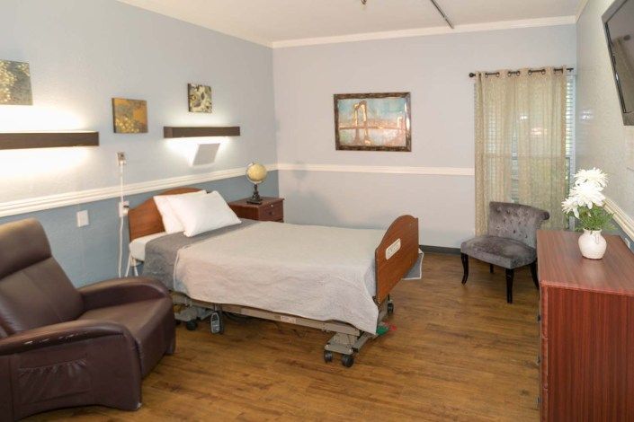A clean and organized hospital room featuring a patient bed, armchair, and decorations.