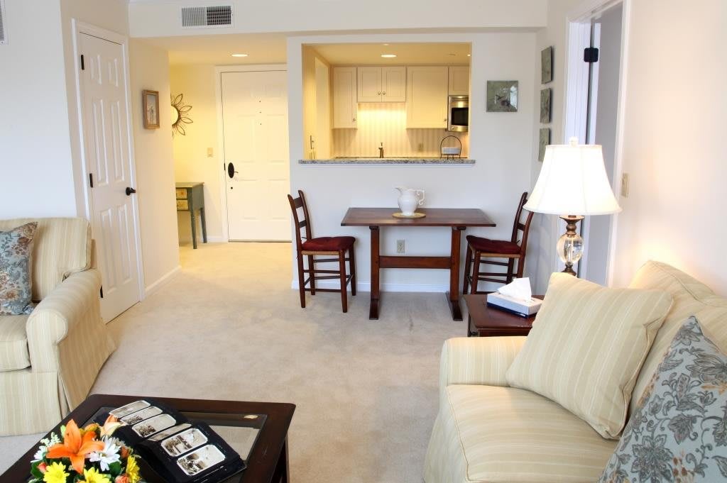 A cozy apartment interior featuring a living room with a small dining area and a view into the kitchen.