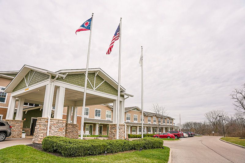 A building with flags and a parking lot on a cloudy day.