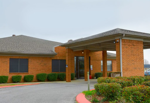 A view of a brick building with an inviting entrance and landscaped surroundings.