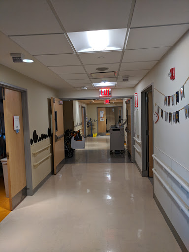 A view of a hospital hallway with doors leading to patient rooms and medical supplies.