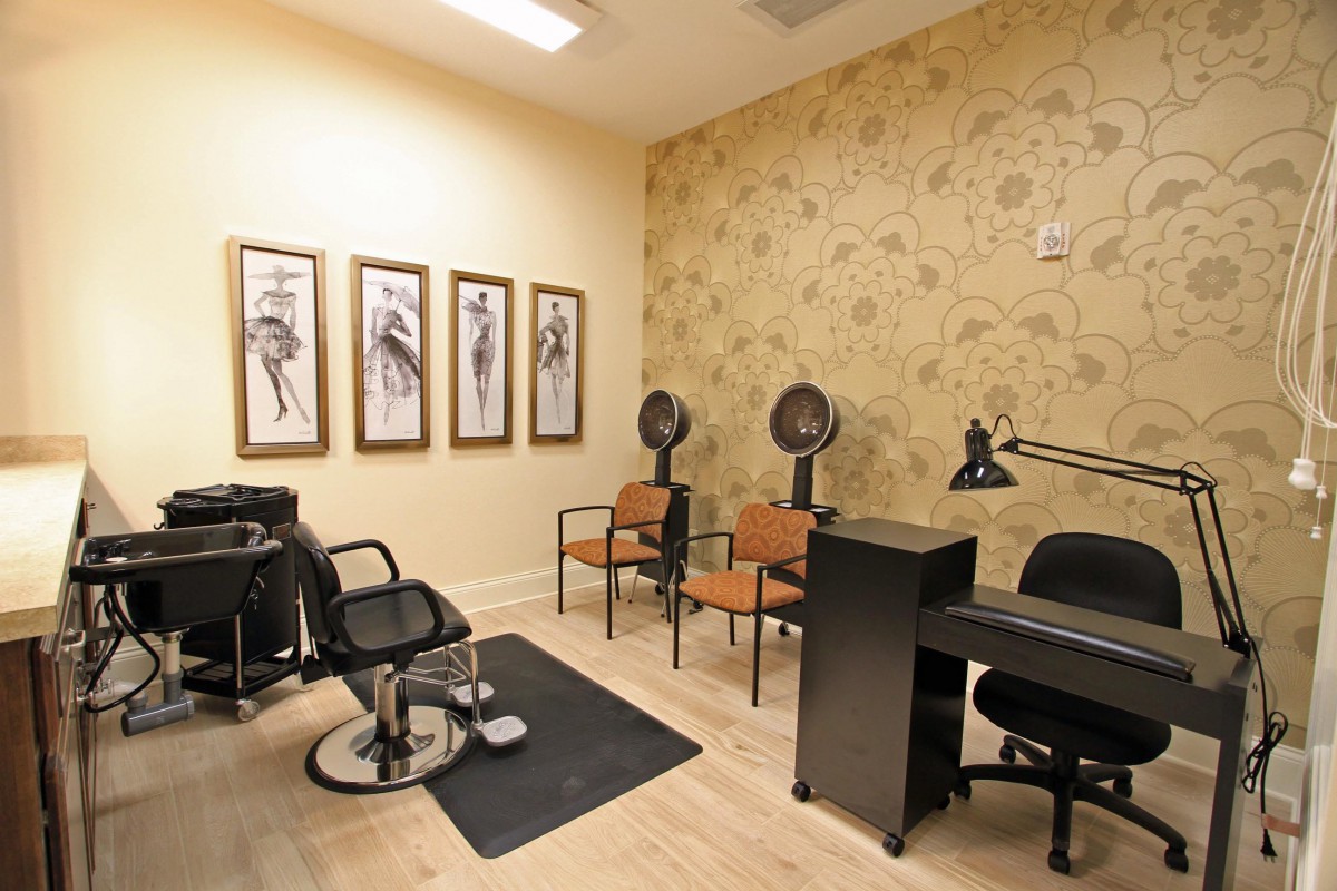 A cozy salon interior featuring styling chairs, hairdryers, and elegant artwork on the walls.