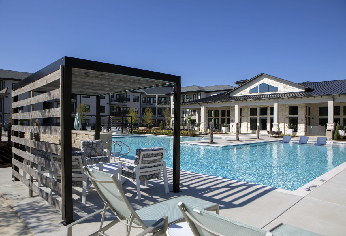 A luxurious outdoor pool area with lounge chairs under a clear blue sky.